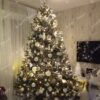 Široko i visoko umjetno božićno drvce, tamnozelenih grana, ukrašeno bijelo-srebrnim ukrasima i bijelom rasvjetom