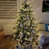 Umjetno božićno drvce s debelim zelenim granama, ukrašeno bijelim ukrasima i bijelom toplom rasvjetom