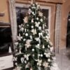 Umjetno božićno drvce sa zelenim granama, ukrašeno bijelim ukrasima, u dnevnoj sobi