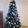 Umjetno božićno drvce s tamnozelenim granama, ukrašeno bijelim i bakrenim ukrasima