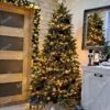 Blijedozeleno umjetno božićno drvce, bogato ukrašeno zlatnim ukrasima, u dnevnoj sobi