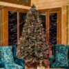 Visoko i široko umjetno božićno drvce, blijedozelenih debelih grana, ukrašeno ljubičastim ukrasima