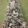 Bijelo umjetno božićno drvce s gusto snijegom prekrivenim granama, ukrašeno bijelim i ružičastim ukrasima, usklađeno s Djedom Božićnjakom