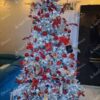 Visoko umjetno božićno drvce sa snježnim granama, s crvenim ukrasima i bijelom rasvjetom