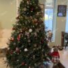 Visoko i masivno umjetno božićno drvce u dnevnoj sobi, ukrašeno crvenim i zlatnim ukrasima.