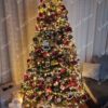 Umjetno božićno drvce sa snježnim krajevima grana, ukrašeno šišarkama i bobicama, bogato ukrašeno