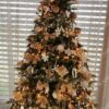 Umjetno božićno drvce ukrašeno zlatnim ukrasima i toplom rasvjetom