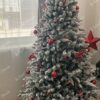 Bijelo božićno drvce ukrašeno crvenim mašnicama i kuglicama