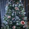 Zeleno božićno drvce sa ružama i bijelim ukrasima u dnevnoj sobi