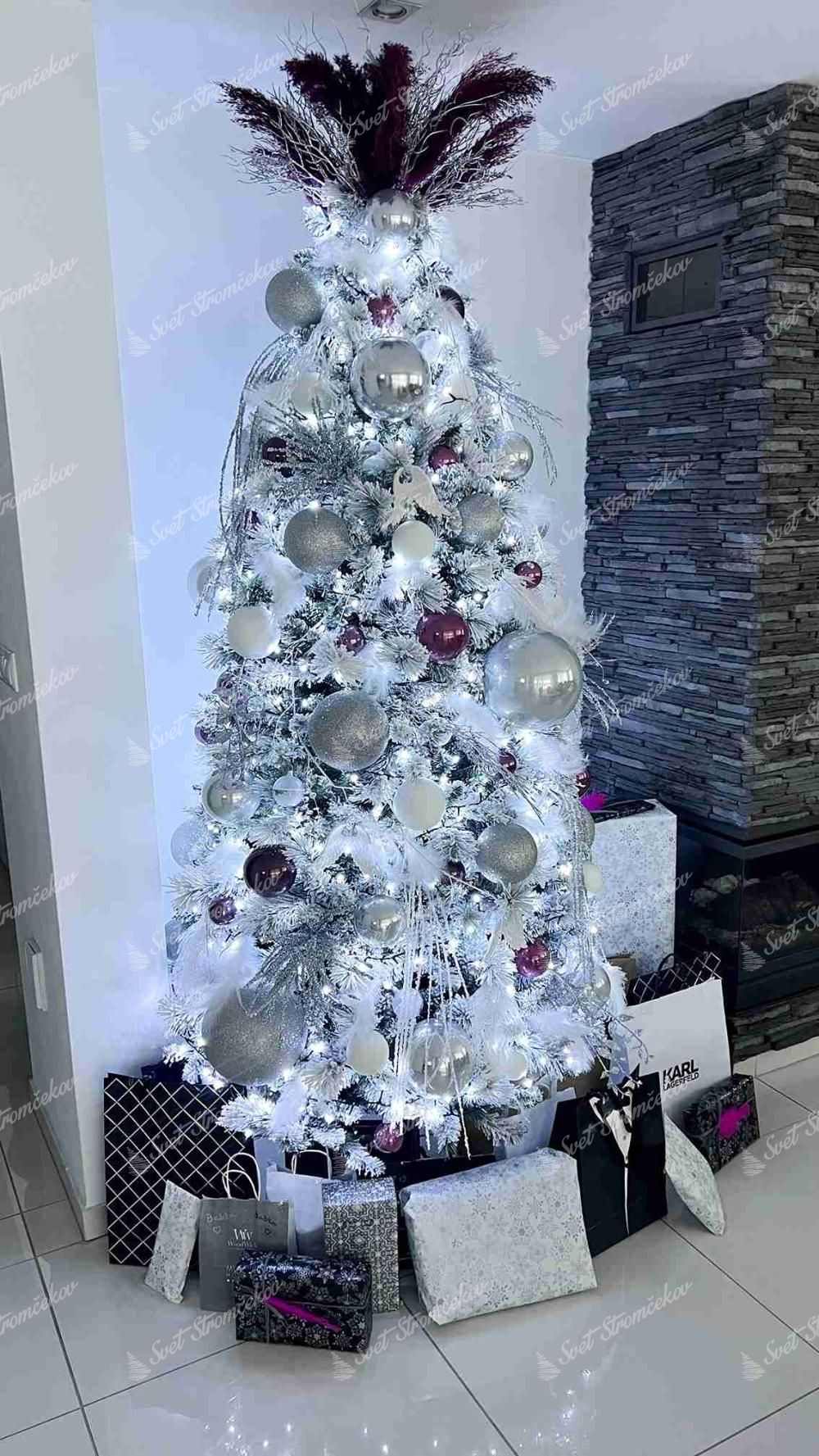 Umelý vianočný stromček Borovica Biela Úzka 225cm, stromček má husto zasnežené vetvičky a je ozdobený striebornými a čiernymi ozdobami